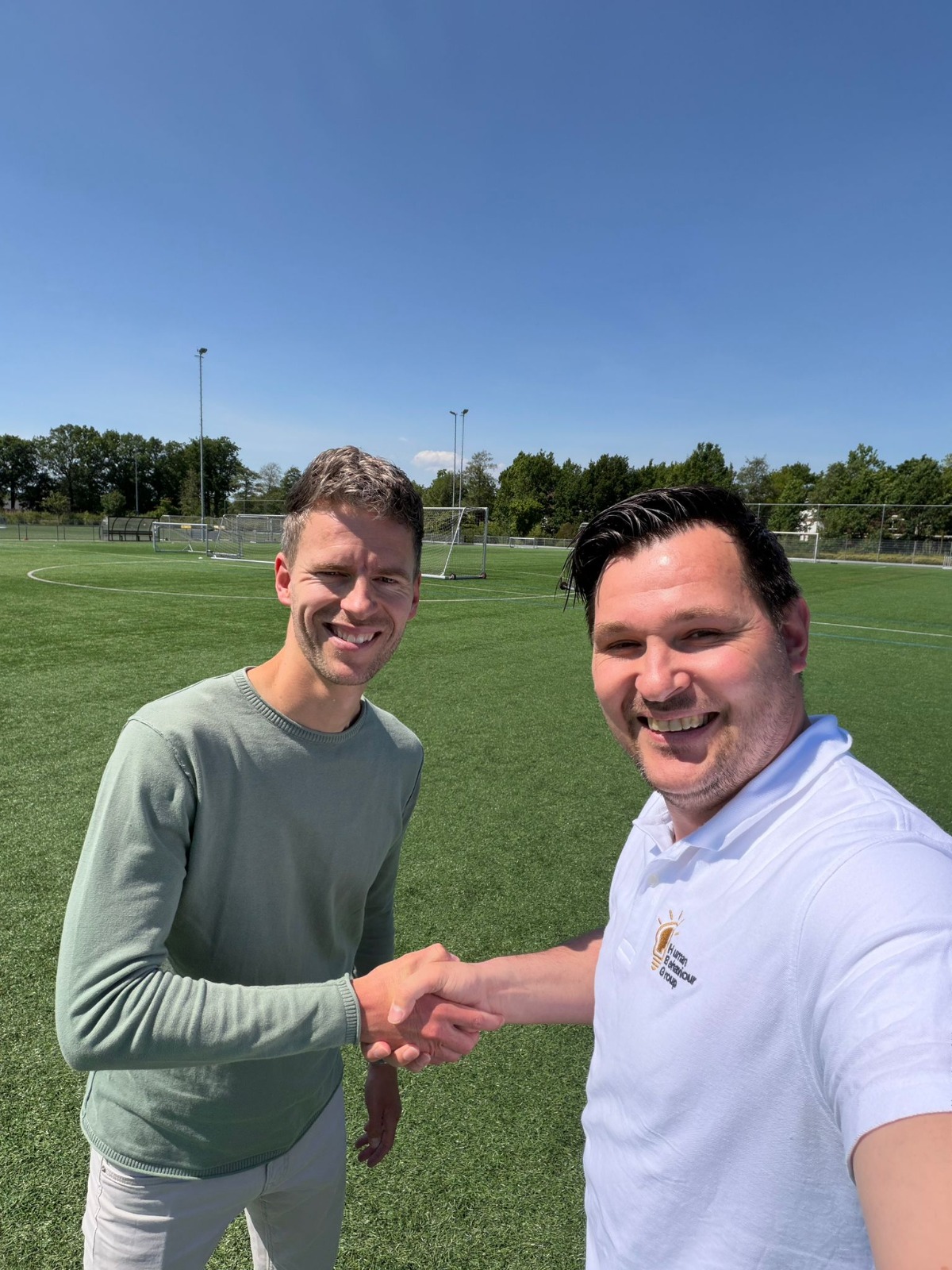 Roald de Vries en Theo Brack bezegelen de samenwerking met een handshake op het voetbalveld